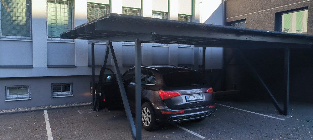 Solární carport s parkujícím autem u firemní budovy
